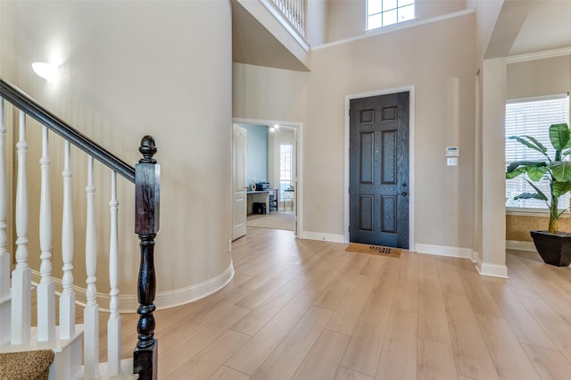 entryway featuring a high ceiling, a healthy amount of sunlight, and light hardwood / wood-style floors