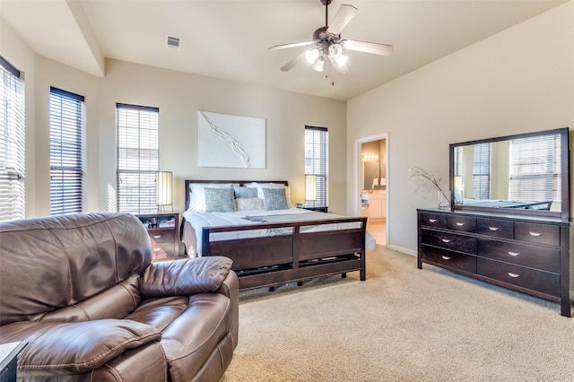 carpeted bedroom with multiple windows, ceiling fan, and ensuite bathroom