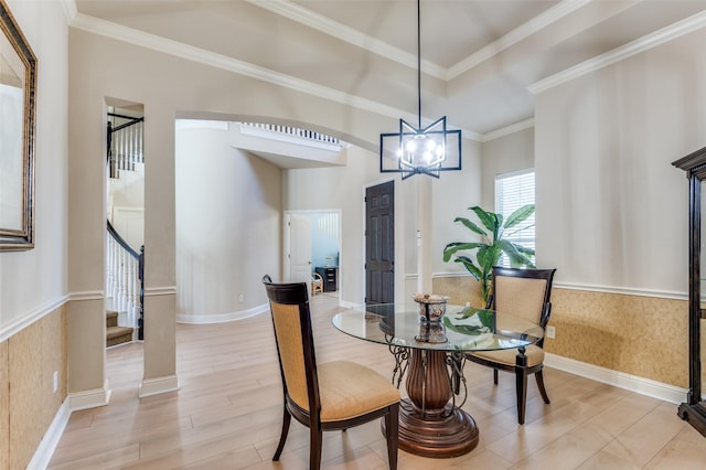 dining space featuring a tray ceiling, light hardwood / wood-style flooring, ornamental molding, and a chandelier