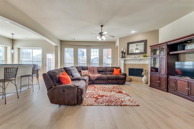 living room featuring ceiling fan, a fireplace, and light hardwood / wood-style flooring