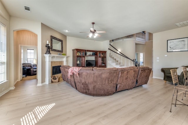 living room featuring ceiling fan, a fireplace, and light hardwood / wood-style floors