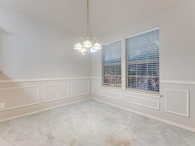 carpeted spare room featuring a chandelier