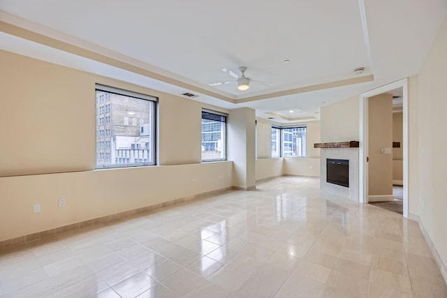 unfurnished living room featuring a raised ceiling, a tiled fireplace, light tile patterned floors, and ceiling fan