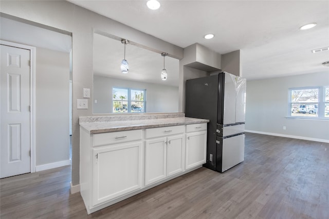 kitchen featuring white cabinetry, hanging light fixtures, stainless steel fridge, and light hardwood / wood-style floors