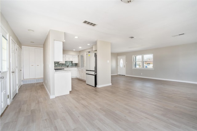 kitchen with white cabinetry, decorative backsplash, light wood-type flooring, and white fridge