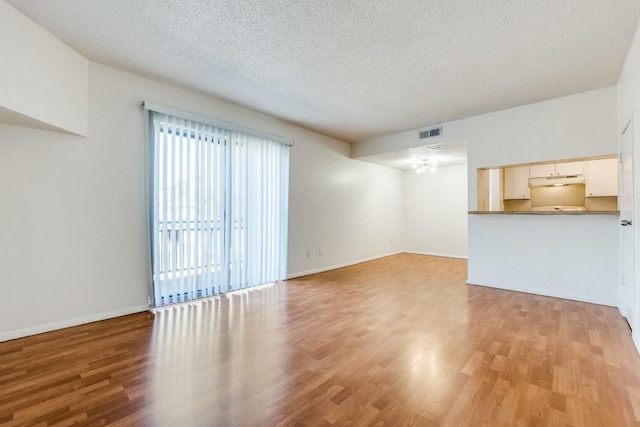 unfurnished living room featuring light hardwood / wood-style flooring and a textured ceiling