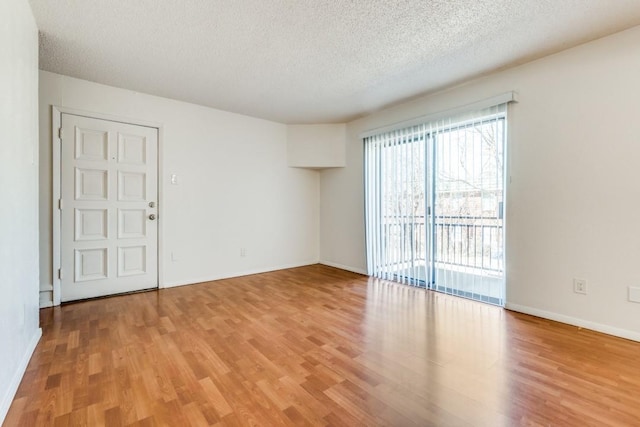 spare room with a textured ceiling and light wood-type flooring