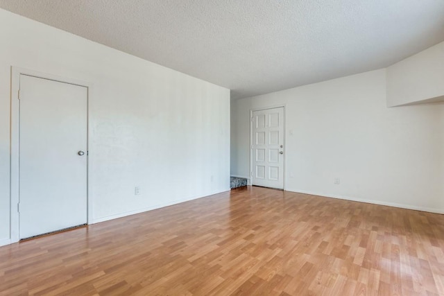 spare room with a textured ceiling and light wood-type flooring