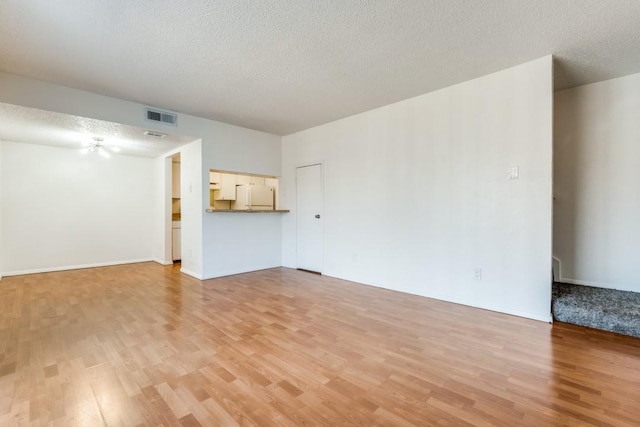 unfurnished living room featuring light hardwood / wood-style flooring and a textured ceiling