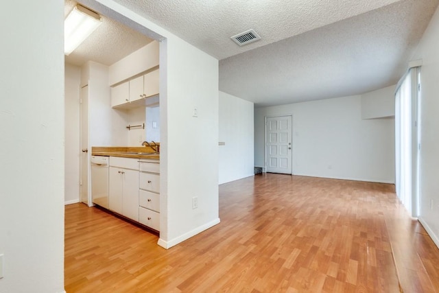 kitchen featuring dishwasher, white cabinets, a textured ceiling, and light hardwood / wood-style flooring