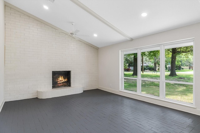 unfurnished living room featuring ceiling fan, lofted ceiling, brick wall, and a brick fireplace