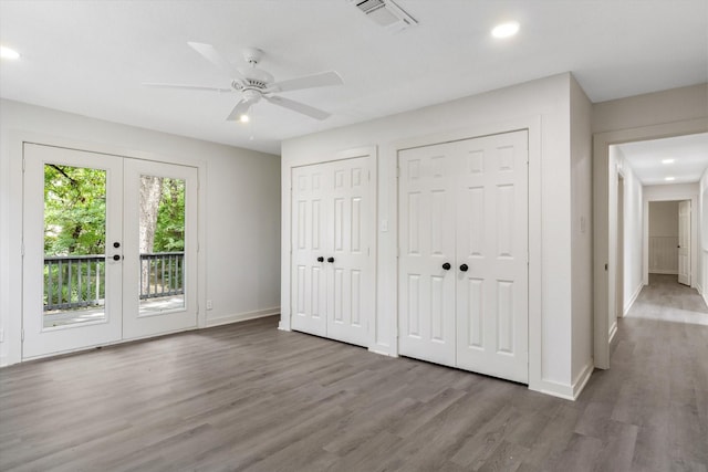 unfurnished bedroom featuring hardwood / wood-style flooring, ceiling fan, two closets, access to outside, and french doors