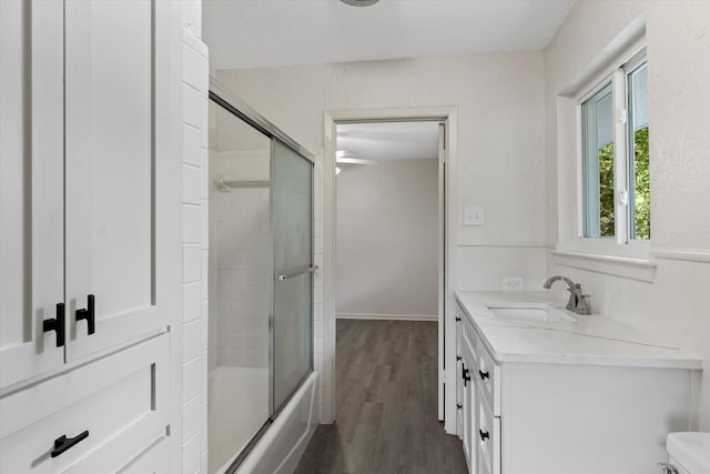 full bathroom featuring hardwood / wood-style flooring, vanity, combined bath / shower with glass door, and toilet