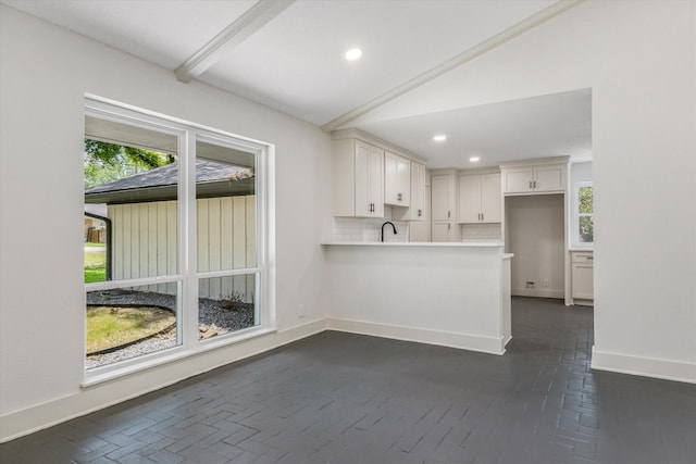 kitchen featuring sink, tasteful backsplash, lofted ceiling with beams, kitchen peninsula, and white cabinets