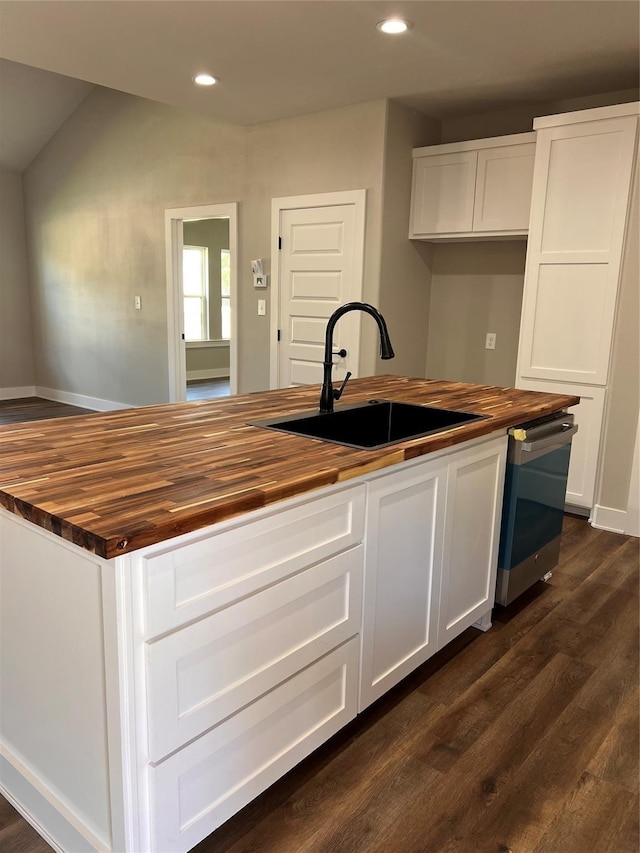 kitchen featuring white cabinets, dark wood finished floors, a sink, wooden counters, and stainless steel dishwasher