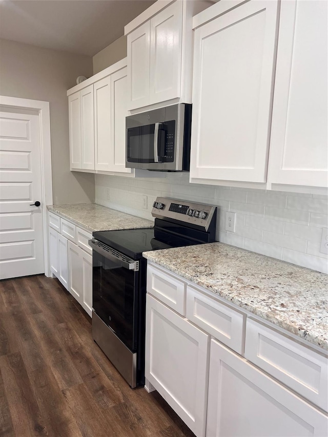 kitchen featuring dark wood-style flooring, white cabinets, appliances with stainless steel finishes, light stone countertops, and tasteful backsplash