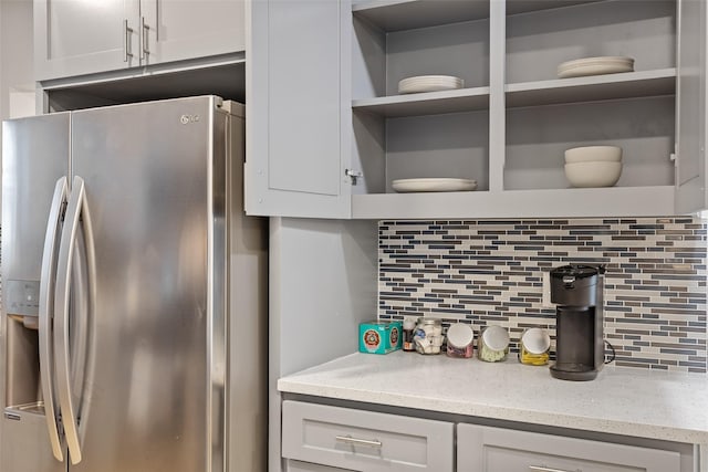 kitchen with stainless steel refrigerator with ice dispenser, decorative backsplash, and white cabinets