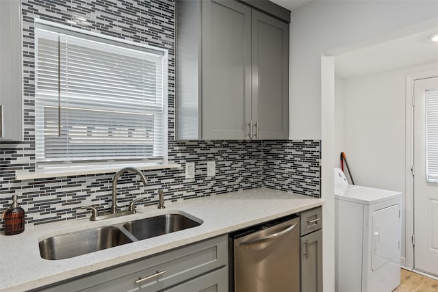 kitchen with dishwasher, washer / dryer, sink, and light stone counters