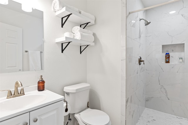 bathroom featuring vanity, toilet, and a tile shower