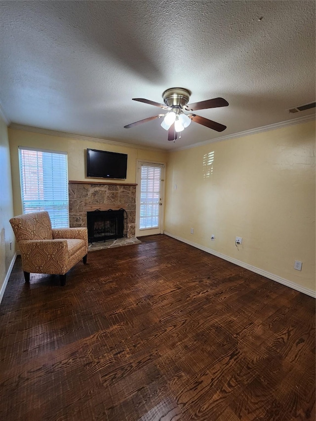 unfurnished living room featuring a stone fireplace, crown molding, wood-type flooring, a textured ceiling, and ceiling fan