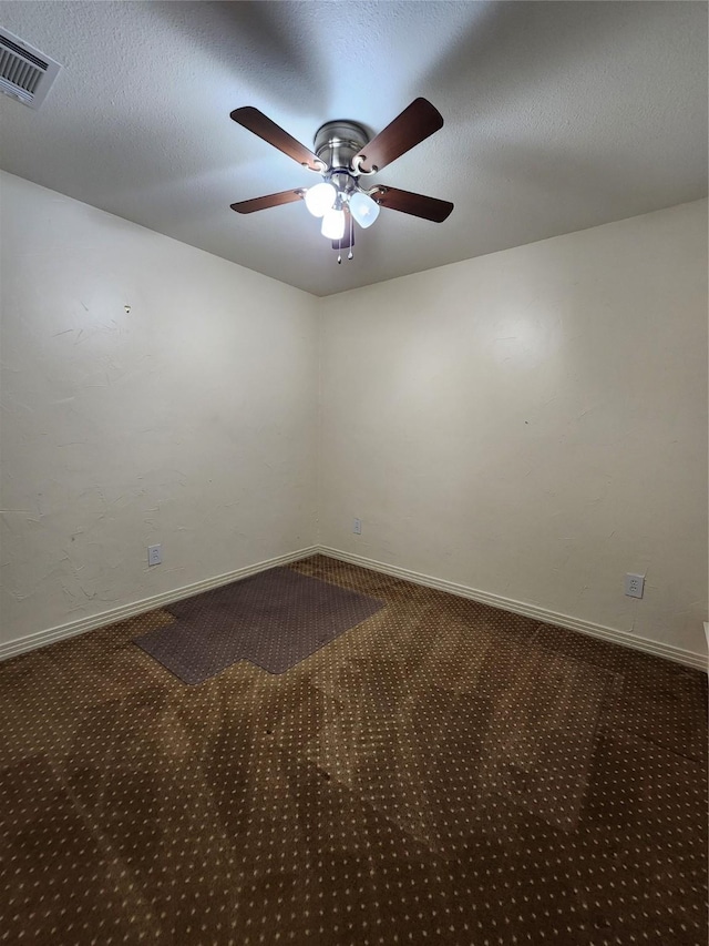 spare room featuring ceiling fan, a textured ceiling, and dark carpet