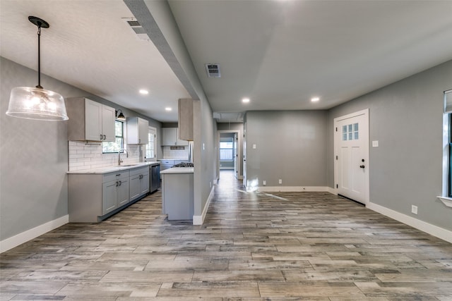 kitchen with decorative light fixtures, tasteful backsplash, sink, gray cabinetry, and light hardwood / wood-style floors