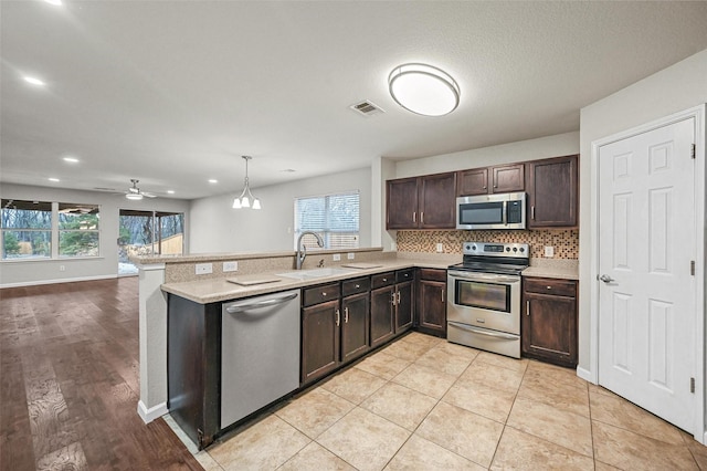 kitchen featuring light countertops, visible vents, appliances with stainless steel finishes, a sink, and a peninsula