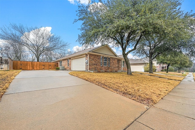 view of front facade featuring brick siding, concrete driveway, central AC unit, fence, and a garage