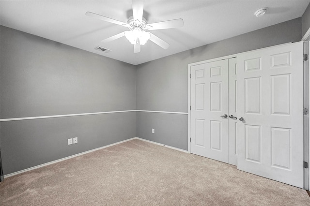 unfurnished bedroom featuring a closet, visible vents, a ceiling fan, carpet flooring, and baseboards