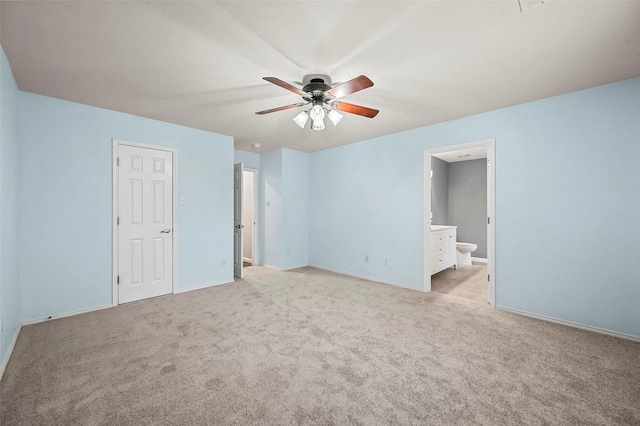 unfurnished bedroom with light carpet, baseboards, and ensuite bathroom