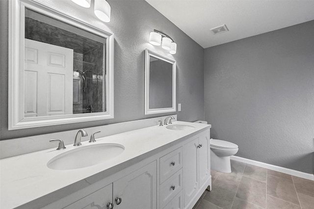 bathroom with visible vents, a sink, toilet, and double vanity