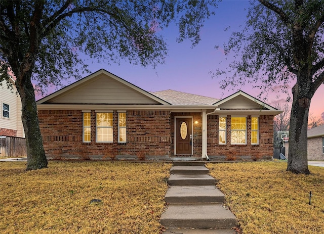 single story home featuring a porch, brick siding, and a yard