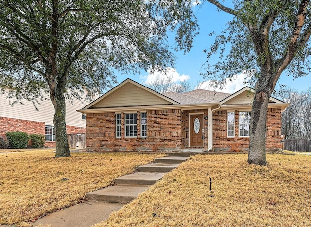 single story home featuring brick siding, a front lawn, a shingled roof, and fence