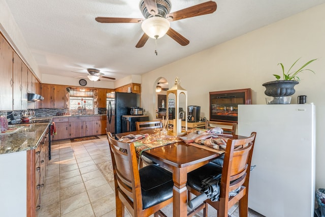 dining area with ceiling fan, sink, light tile patterned floors, and a textured ceiling