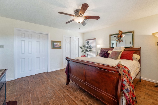 bedroom with multiple closets, dark hardwood / wood-style floors, a textured ceiling, and ceiling fan