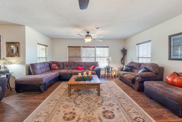 living room with dark wood-type flooring, ceiling fan, and a textured ceiling