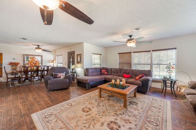 living room with dark wood-type flooring, ceiling fan, and a textured ceiling