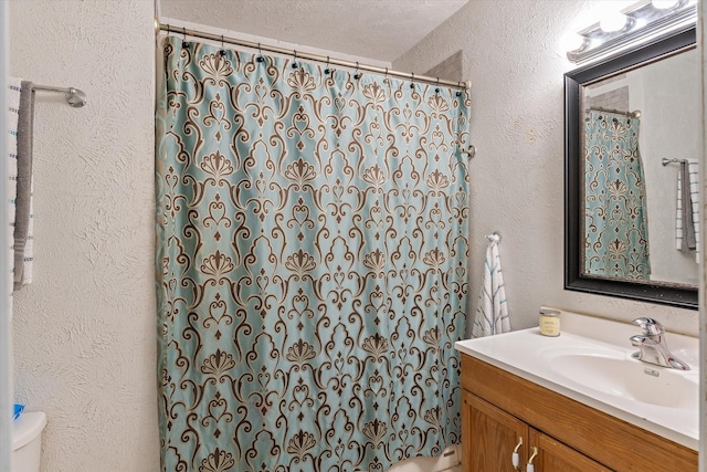 bathroom with vanity, curtained shower, a textured ceiling, and toilet