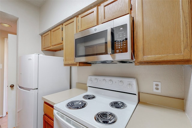 kitchen featuring light brown cabinets and white appliances