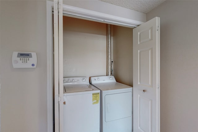 laundry area with independent washer and dryer and a textured ceiling