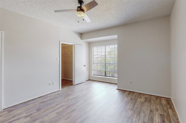 unfurnished room with ceiling fan, a textured ceiling, and light hardwood / wood-style flooring