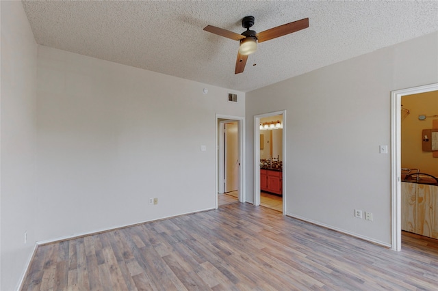 unfurnished bedroom featuring connected bathroom, light hardwood / wood-style floors, a textured ceiling, and ceiling fan