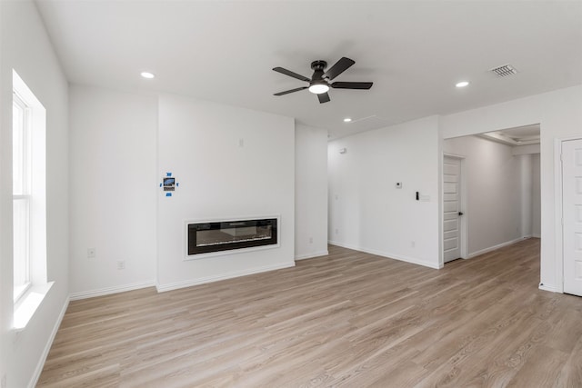 unfurnished living room with baseboards, ceiling fan, recessed lighting, light wood-style floors, and a glass covered fireplace