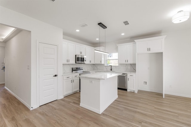 kitchen featuring light wood-type flooring, a kitchen island, appliances with stainless steel finishes, and white cabinetry