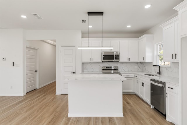 kitchen with light wood-type flooring, a sink, backsplash, white cabinetry, and stainless steel appliances