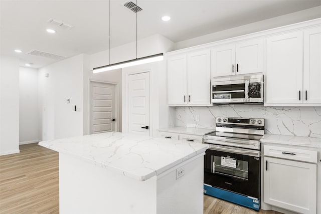 kitchen featuring a kitchen island, visible vents, stainless steel appliances, and tasteful backsplash