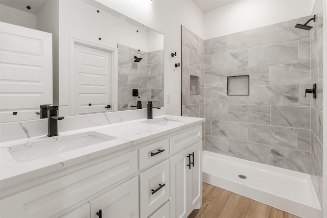 bathroom featuring tiled shower, wood finished floors, and a sink