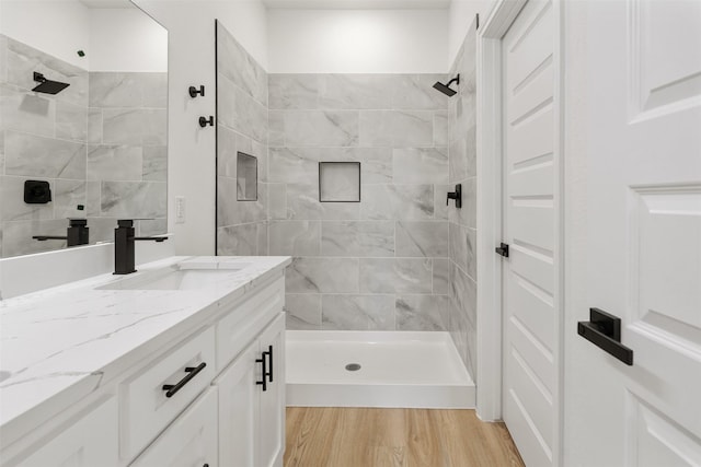 bathroom with vanity, wood finished floors, and a tile shower