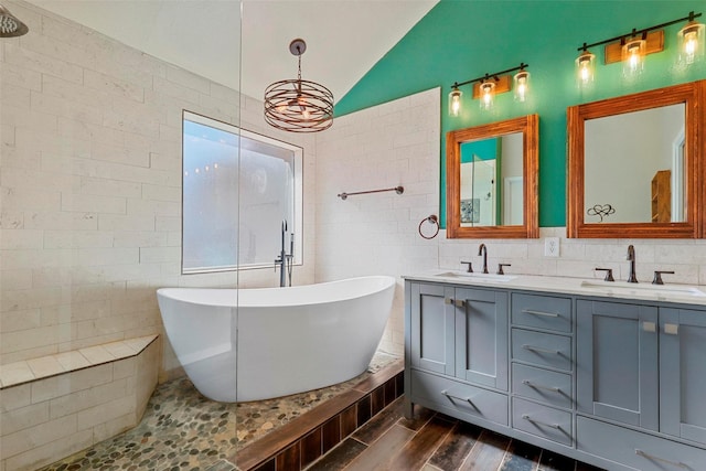 bathroom featuring vaulted ceiling, tile walls, vanity, a tub, and hardwood / wood-style floors