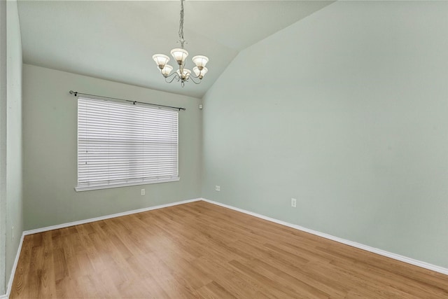 spare room with an inviting chandelier, lofted ceiling, and light wood-type flooring